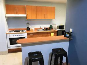 a kitchen with wooden cabinets and a counter with stools at DOWNTOWN APT Pool & Gym in Mexico City