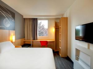 um quarto de hotel com uma cama e uma televisão em ibis Clermont Ferrand Nord Riom em Riom