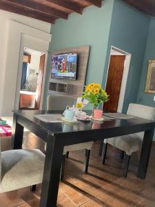 Una mesa de comedor negra con sillas y flores. en Hospedaje Umma-Ezeiza, en Ezeiza