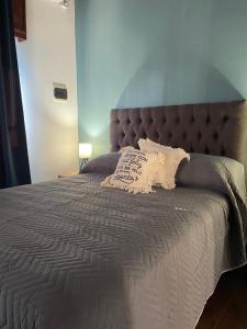 Una cama grande con una colcha gris y una almohada. en Hospedaje Umma-Ezeiza, en Ezeiza