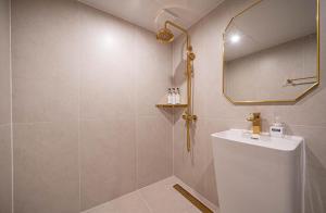 a bathroom with a shower with a sink and a mirror at Denbasta Hotel Choeup in Busan