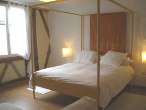 1 dormitorio con cama con dosel, sábanas y almohadas blancas en Les Terraces Sur La Dordogne, en Sainte-Foy-la-Grande