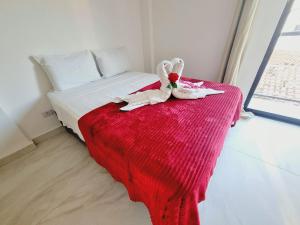 a bed with a stuffed animal on a red blanket at Ap no Coração de Porto de Galinhas Paulo Brito 101 - By Anfitrião Legal in Porto De Galinhas +29 photos