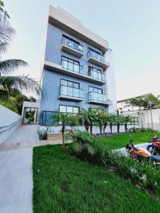 a blue building with palm trees in front of it at Ap no Coração de Porto de Galinhas Paulo Brito 101 - By Anfitrião Legal in Porto De Galinhas