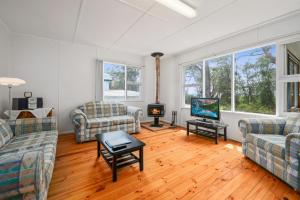 un salon avec deux canapés et une télévision dans l'établissement On Collingwood Beach - Upstairs Apartment, à Vincentia