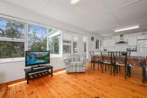 un salon avec une télévision et une salle à manger dans l'établissement On Collingwood Beach - Upstairs Apartment, à Vincentia