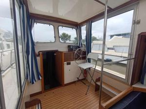 a small boat with a room with windows at Séjour atypique sur une Pénichette vintage avec terrasse - Pontailler-sur-Saône - API-1-46-20 in Pontailler-sur-Saône