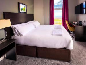 a large bed in a hotel room with a desk and a bed sidx sidx sidx at The Esplanade Hotel by Compass Hospitality in Paignton