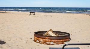 a tub on a beach with the ocean in the background at Beach Club of Oscoda - All 4 Beachfront Cottages in Oscoda