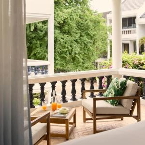 a porch with two chairs and a table on a balcony at Dolly Beach House by Yudee Assets in Hua Hin