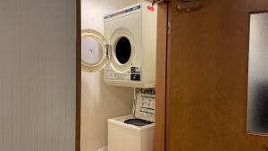 ein Badezimmer mit einer Waschmaschine über einer Toilette in der Unterkunft Hakodate Hotel Ekimae - Vacation STAY 91824v in Hakodate + 4 Fotos