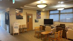 una sala d'attesa con tavoli, sedie e TV di Hakodate Hotel Ekimae - Vacation STAY 91829v a Hakodate