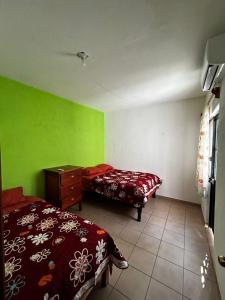 een slaapkamer met twee bedden, een ladekast en groene muren bij Casa Flor de Mayo in Santa Cruz Huatulco +6 foto's