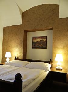 a bedroom with a large white bed with two lamps at Hotel U Kříže in Prague