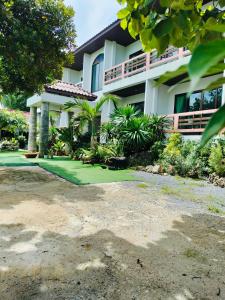a house with a green lawn in front of it at Jigsaw Cafe & Resort in Ban Na We