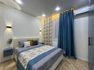 a bedroom with a bed and a window with blue curtains at В шикарном районе Атырау возле дворца ЦЕНТР АБАЯ New City от аэропорта 3 минуты in Atyraū