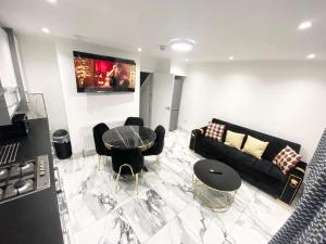 a living room with a black couch and a table at THE ROYAL BOUTIQUE PICCADILLY LODGE by LONDON SLEEP 6 in Hayes