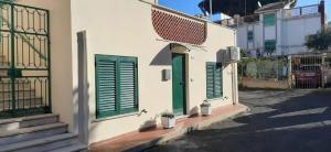 a white building with green shutters on a street at La Casa al mare in Santa Marinella