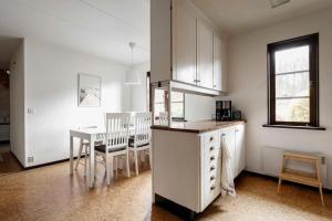 a kitchen with white cabinets and a table and chairs at Grevie skogsvilla in Grevie