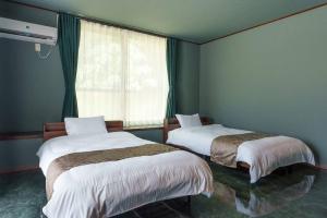 Dos camas en una habitación con ventana. en シャングリラ石垣, en Ishigaki Island