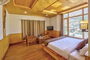 Un dormitorio con una cama, un escritorio y un televisor. en Hotel Regency, en Kulu