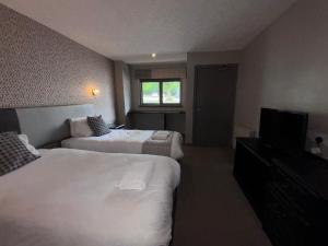 a hotel room with two beds and a television at Richmond Park Hotel in Boʼness