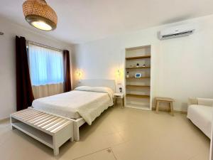 a white bedroom with a bed and a couch at Lotto 16 - Guest House in Olbia