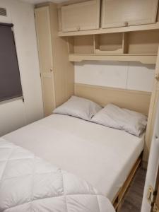 a bed with two pillows in a small room at Le Petit Écrin, caravane résidentielle in Trois-Ponts +44 photos