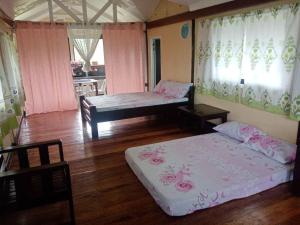 two beds in a room with pink curtains at Davao City-Marilog Peak Cafe- Traveler's Staycation in Davao City