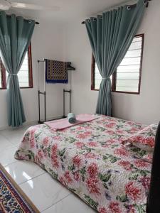 a bedroom with a bed and two windows with curtains at Roomstay Mok House - Unit 2 in Kuala Terengganu