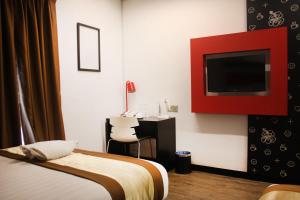 a bedroom with a bed and a desk and a tv at Lazdana Hotel Kuala Lumpur in Kuala Lumpur