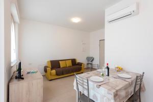 a living room with a table and a yellow couch at Suite Ondina Viareggio Apartments in Viareggio