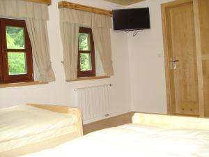 a bedroom with two beds and a tv on the wall at Farmstay Hiša Pečovnik in Luče