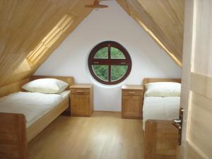2 camas num quarto no sótão com uma janela em Farmstay Hiša Pečovnik em Luče
