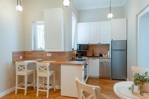 a kitchen with white cabinets and a table and chairs at Old Town Square Apartments Cluj in Cluj-Napoca