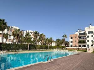 ein Pool mit zwei Stühlen vor einigen Gebäuden in der Unterkunft Bioko I CABO ROIG - Garden, WiFi, Parking, Pool & Sea View in Orihuela
