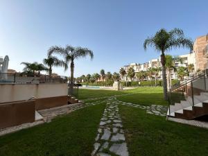 einen Gehweg in einem Park mit Palmen und Gebäuden in der Unterkunft Bioko I CABO ROIG - Garden, WiFi, Parking, Pool & Sea View in Orihuela
