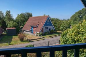 une maison bleue avec un toit rouge sur une route dans l'établissement Dike House Affordable 6-Person Holiday Home Near the Sea Dike, à Anjum