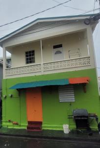 a green and colorful house with a balcony at Shabbehs Inn in Roseau