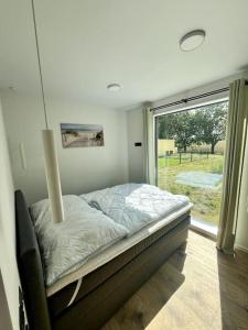 ein Bett in einem Zimmer mit einem großen Fenster in der Unterkunft Ferienhaus Flora in Altefähr