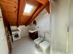 a bathroom with a toilet and a sink and a washing machine at La Casa Dell'Acero in Aymavilles +3 photos