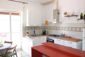 a kitchen with white cabinets and a red counter top at Casa Vinella in Putignano +15 photos