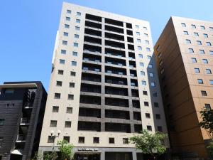 a tall white building in the middle of two buildings at Dormy Inn Kanazawa Natural Hot Spring in Kanazawa