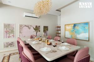 una sala da pranzo con tavolo e sedie rosa di StayVista at The Sweet Sunsation with Jacuzzi, BBQ a Gurgaon