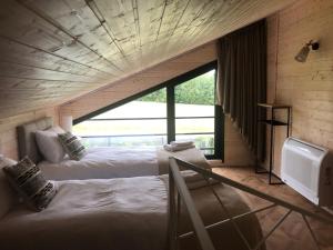 two beds in a room with a large window at Przylesie Domki in Wysoczany