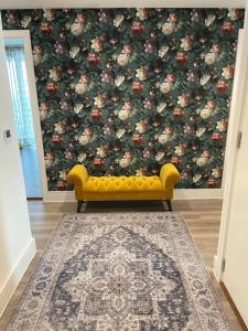 a yellow couch in a living room with a floral wallpaper at Healum Retreat - 3BR Apartment Southall in Southall