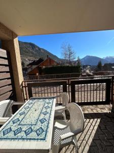 a table and chairs on a balcony with a view of the mountains at Chaleureux appartement moderne in Briançon
