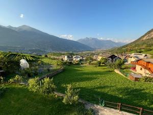 a small village in a green field with mountains at La Casa Dell'Acero in Aymavilles