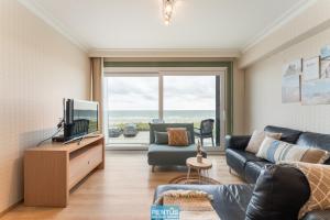 un salon avec un canapé et une télévision dans l'établissement Seanita - sea view apartment in Westende, à Middelkerke