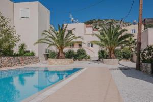 a swimming pool in front of a building with palm trees at Villa Anastasia in Almyrida Beach in Almirida
